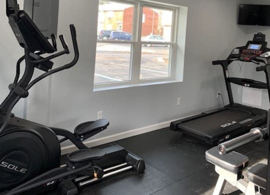 A gym with a treadmill, a stationary bike, and a weight bench.