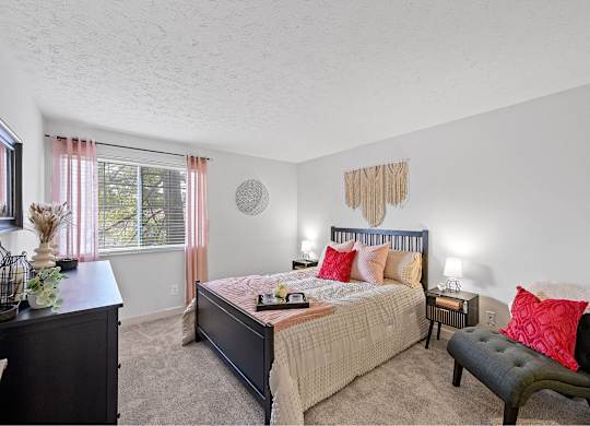 A bedroom with a bed, nightstand, and chair.