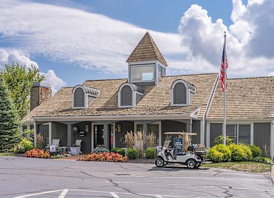 A golf cart is parked in front of a building with an American flag.