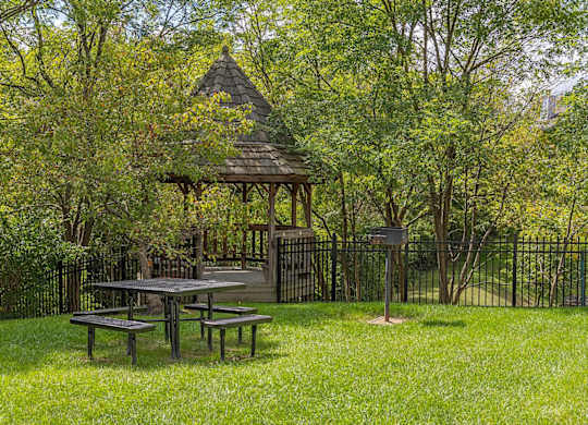 A gazebo is surrounded by a fence and trees.