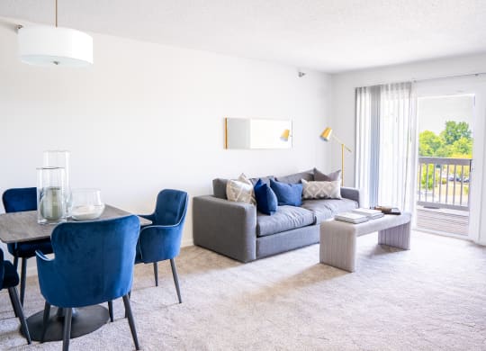 a living room with a couch table and chairs and a sliding glass door leading to a balcony