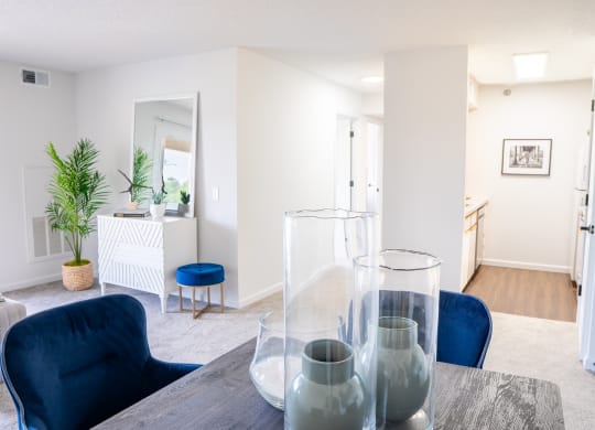 a living room with white walls and a wooden table with blue chairs