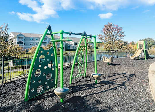 A playground with a green swing set and a slide.