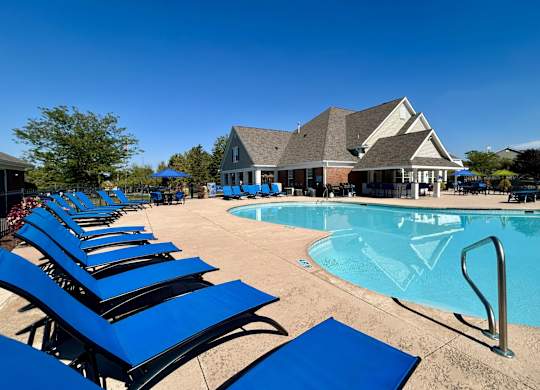 A pool with blue sun loungers and a building in the background.