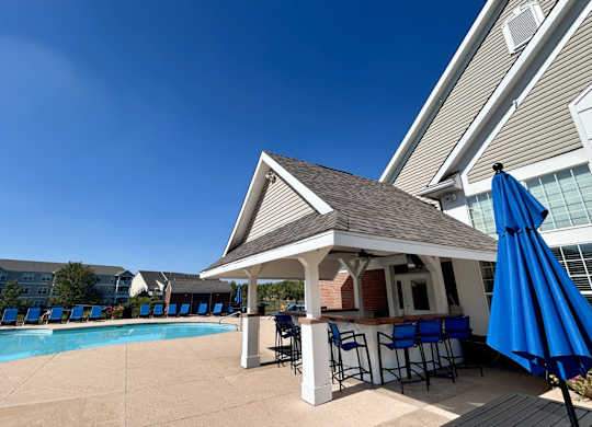 A poolside bar area with a gazebo and blue umbrellas.