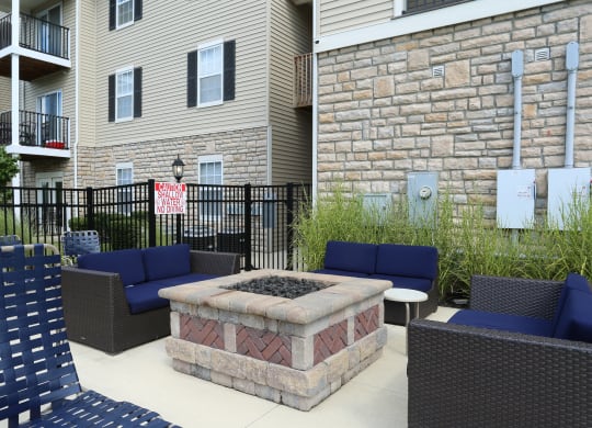 an outdoor patio with a fire pit and chairs in front of an apartment building