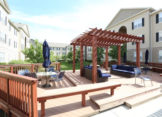 a patio with a wooden pergola and furniture