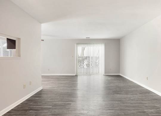A large empty room with a wooden floor and white walls.