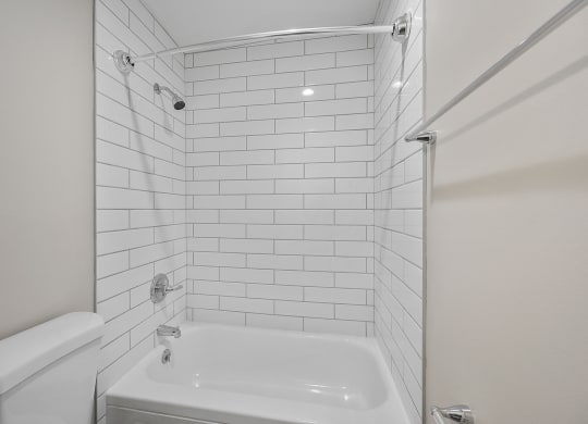 a bathroom with white subway tile and a white bathtub