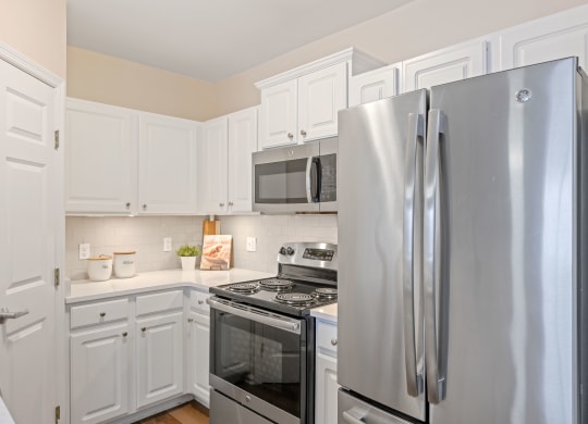 a kitchen with white cabinets and stainless steel appliances at Roebling Row, Kentucky