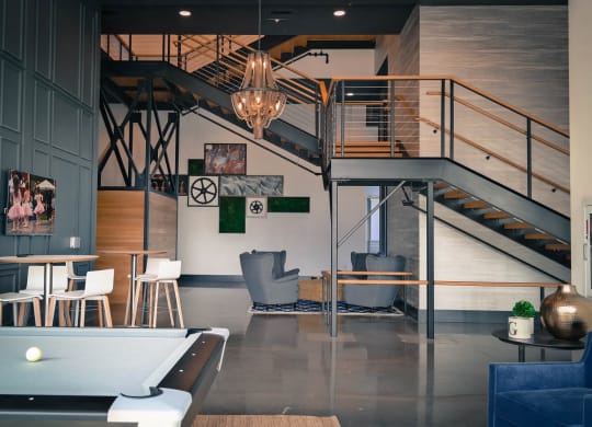a living room with a pool table and stairs