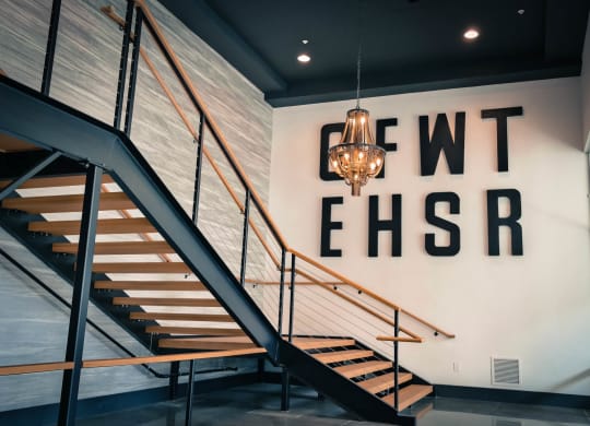 a staircase with a chandelier in front of a wall with a large sign