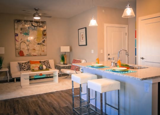 a kitchen with an island and stools in front of a living room with a couch at DeSales Flats Apartments*, Cincinnati, OH