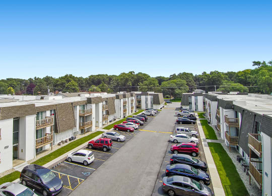 an aerial view of an apartment complex with cars parked on the side of the road