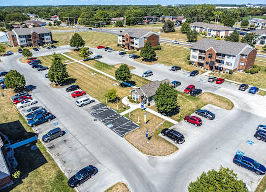 A parking lot with cars and a small building in the background.