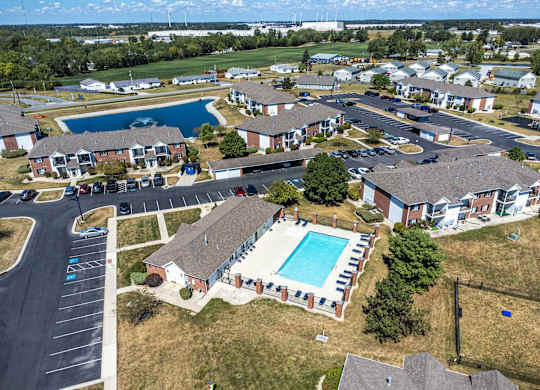 A bird's eye view of a residential area with houses, swimming pools, and a parking lot.