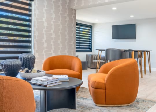 a living room with orange chairs and a table