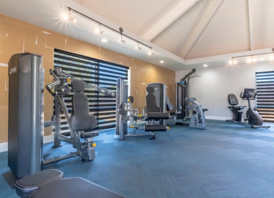 a gym with weights and cardio equipment in a building with white walls