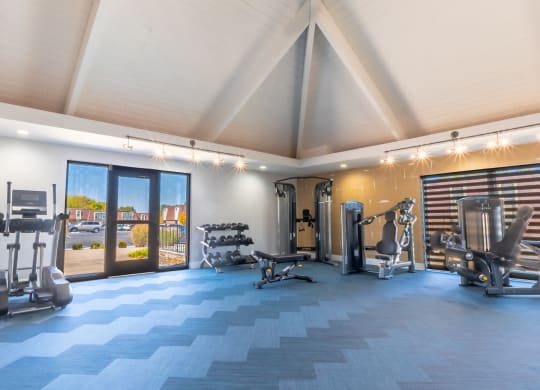 a gym with weights and cardio equipment and a glass door
