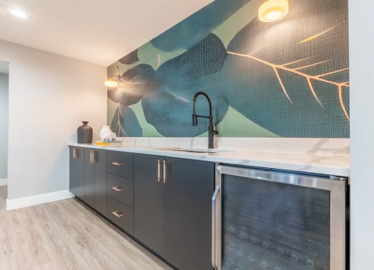 a kitchen with black cabinets and a sink and a painting on the wall