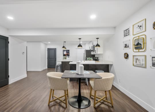 a dining area with a table and chairs and a kitchen in the background