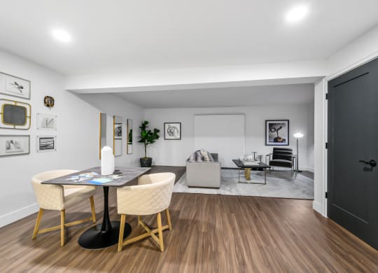 a dining area with a table and chairs and a couch in the background