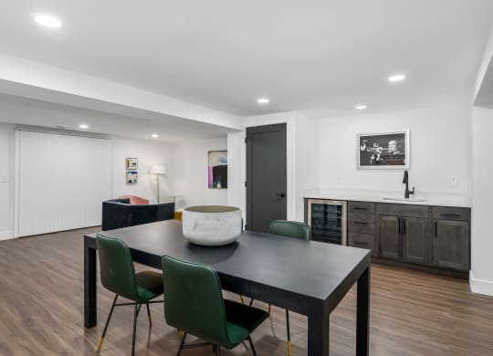 a dining area with a table and chairs and a kitchen in the background