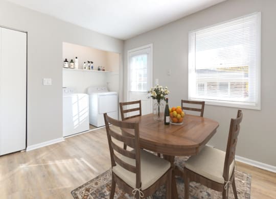 a dining room with a wooden table and chairs and a kitchen with a washing machine at Stonebrook of Franklin, Franklin, 46131