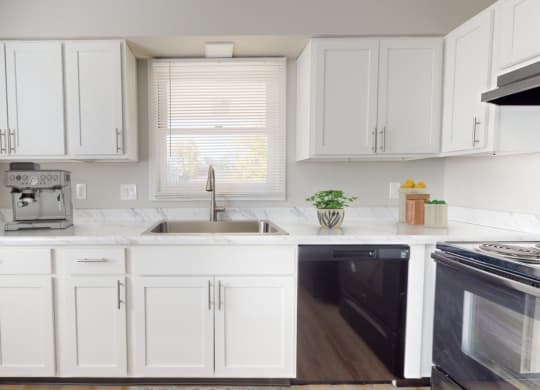 a white kitchen with white cabinets and black appliances and a window at Stonebrook of Franklin, Franklin, IN, 46131