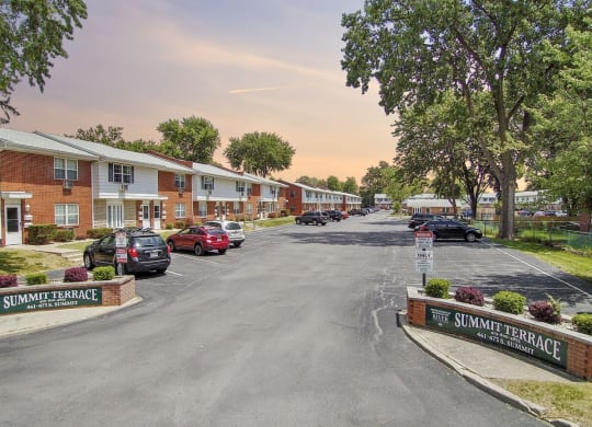 a street with houses and cars parked in a parking lot