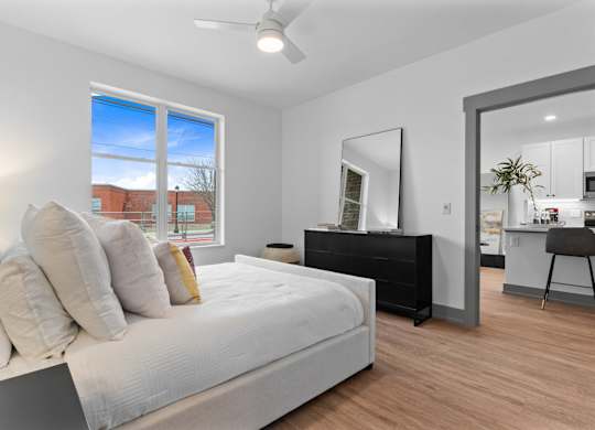 A bedroom with a large bed and a dresser with a mirror. at The Ridge Apartments, Cincinnati, Ohio