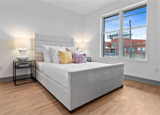 A bedroom with a large bed and a window overlooking a cityscape. at The Ridge Apartments, Ohio