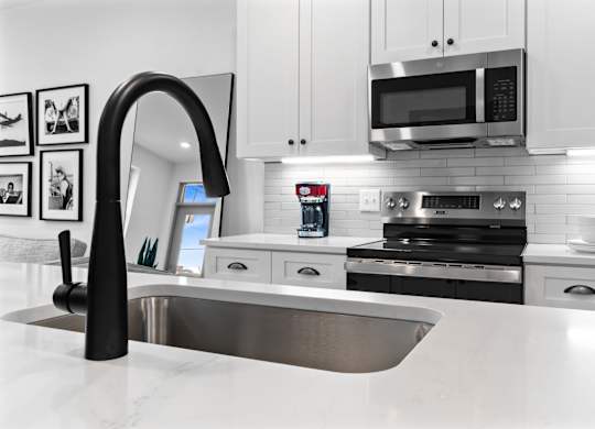 A modern kitchen with a stainless steel sink and white cabinets. at The Ridge Apartments, Ohio, 45213