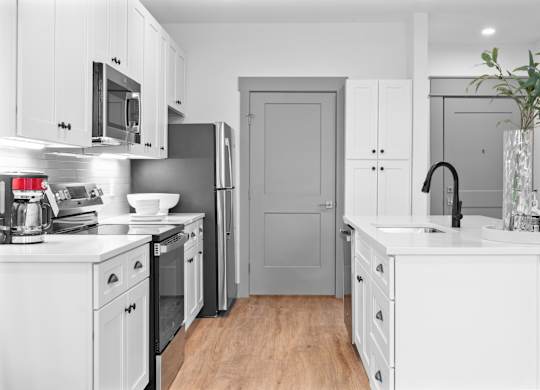A modern kitchen with white cabinets and a wooden floor. at The Ridge Apartments, Cincinnati, OH