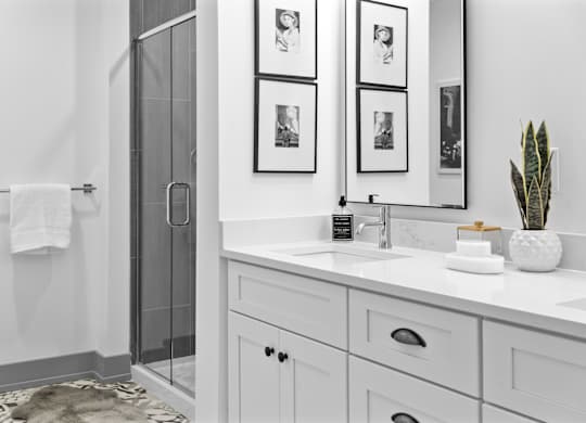 A bathroom with a white sink, a mirror, and a glass shower door. at The Ridge Apartments, Cincinnati, Ohio