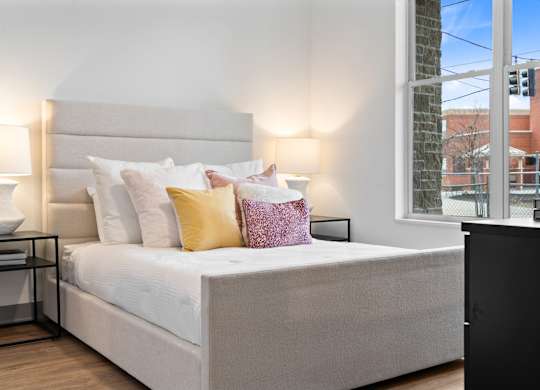 A bed with a white headboard and a white bedspread with multiple pillows. at The Ridge Apartments, Cincinnati, Ohio