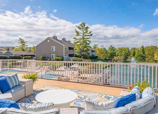 A house with a pool and a deck with a white table and chairs.