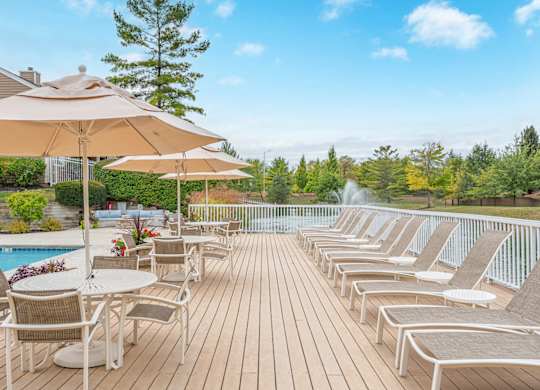 A poolside deck with chairs and umbrellas overlooking a pool.