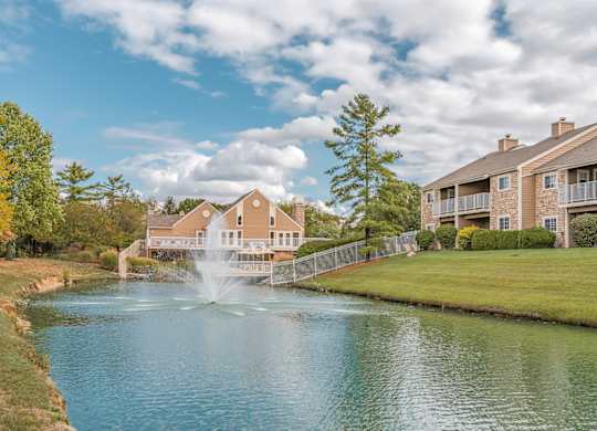 A fountain in the middle of a lake in front of a building.