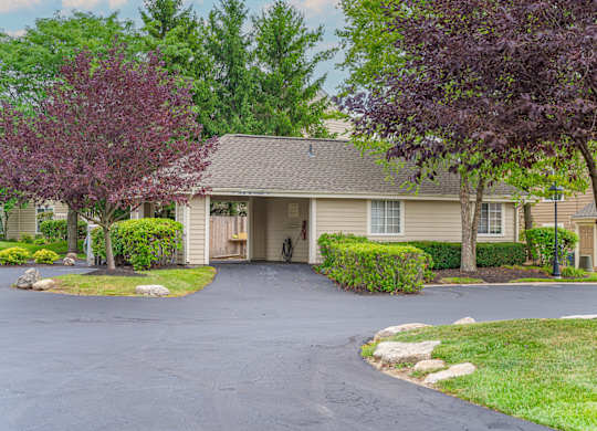 A house with a driveway and trees in front.