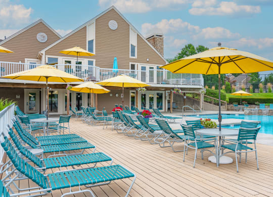 a swimming pool with chaise lounge chairs and umbrellas at Enclave, Beavercreek, OH