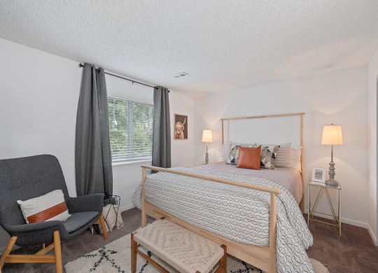 Bedroom with a bed and a chair  at Timber Glen Apartments, Batavia