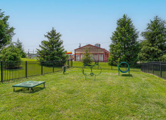 a yard with a swing set and a fence with a house in the background