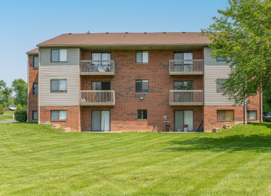 a brick apartment building with balconies and a green lawn