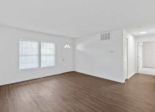 an empty living room with wood flooring and white walls