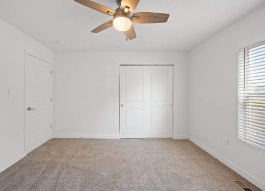 an empty living room with a ceiling fan and a door
