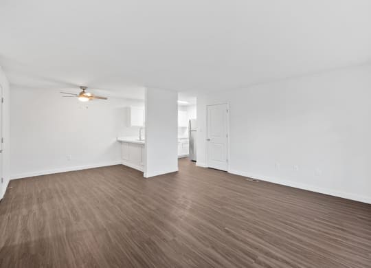 an empty living room with wood flooring and a ceiling fan