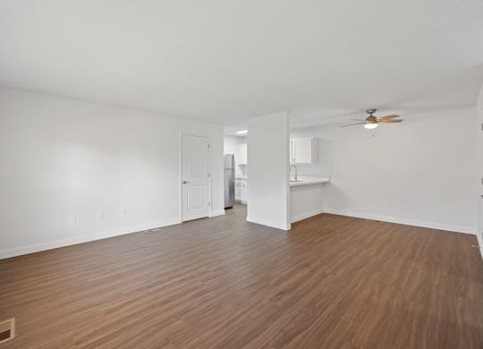 an empty living room with wood flooring and a ceiling fan