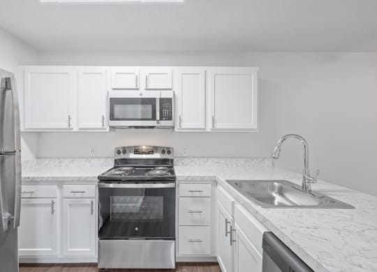 an empty kitchen with white cabinets and stainless steel appliances