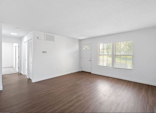 an empty living room with wood floors and white walls